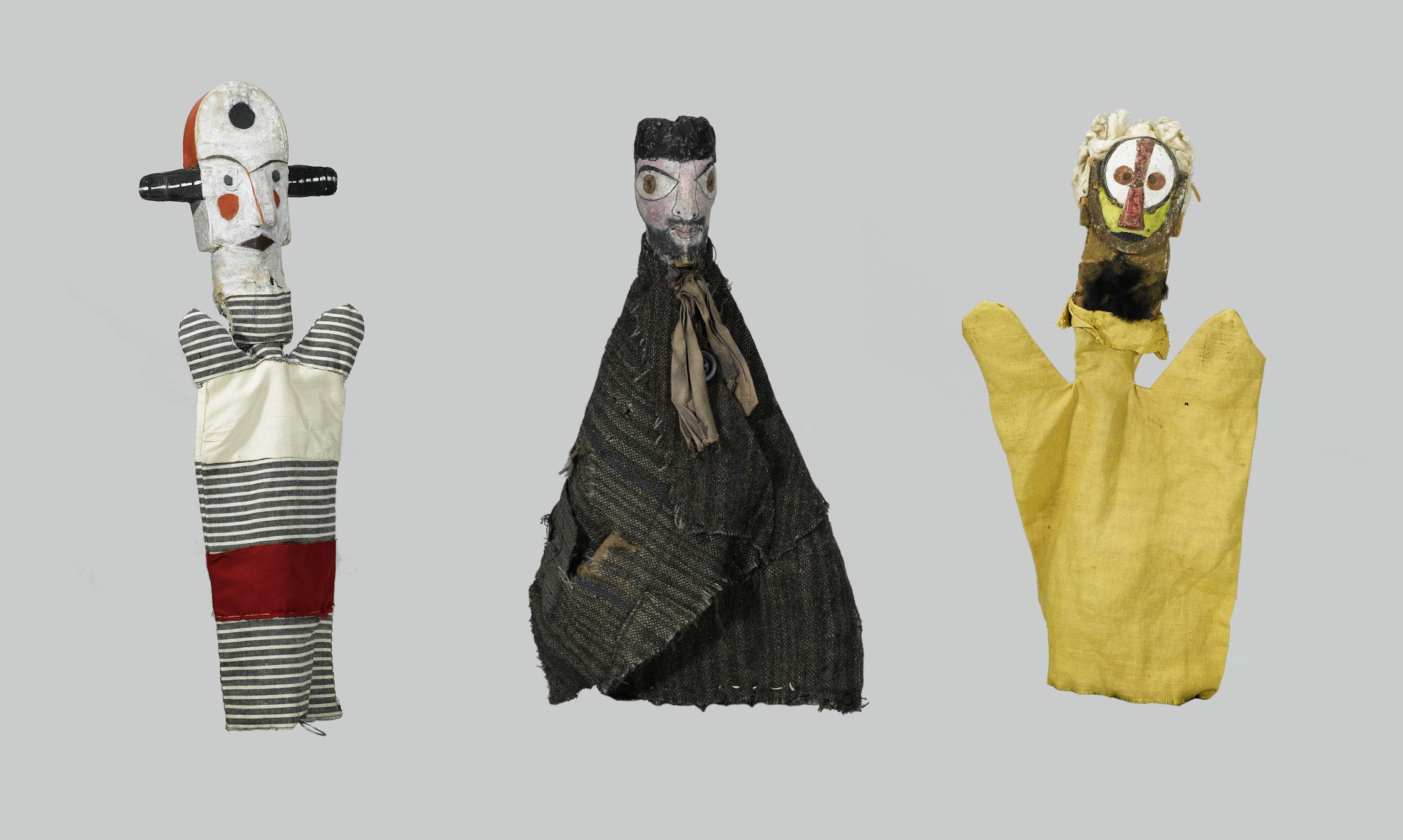 Three antique hand puppets displayed against a neutral gray background.