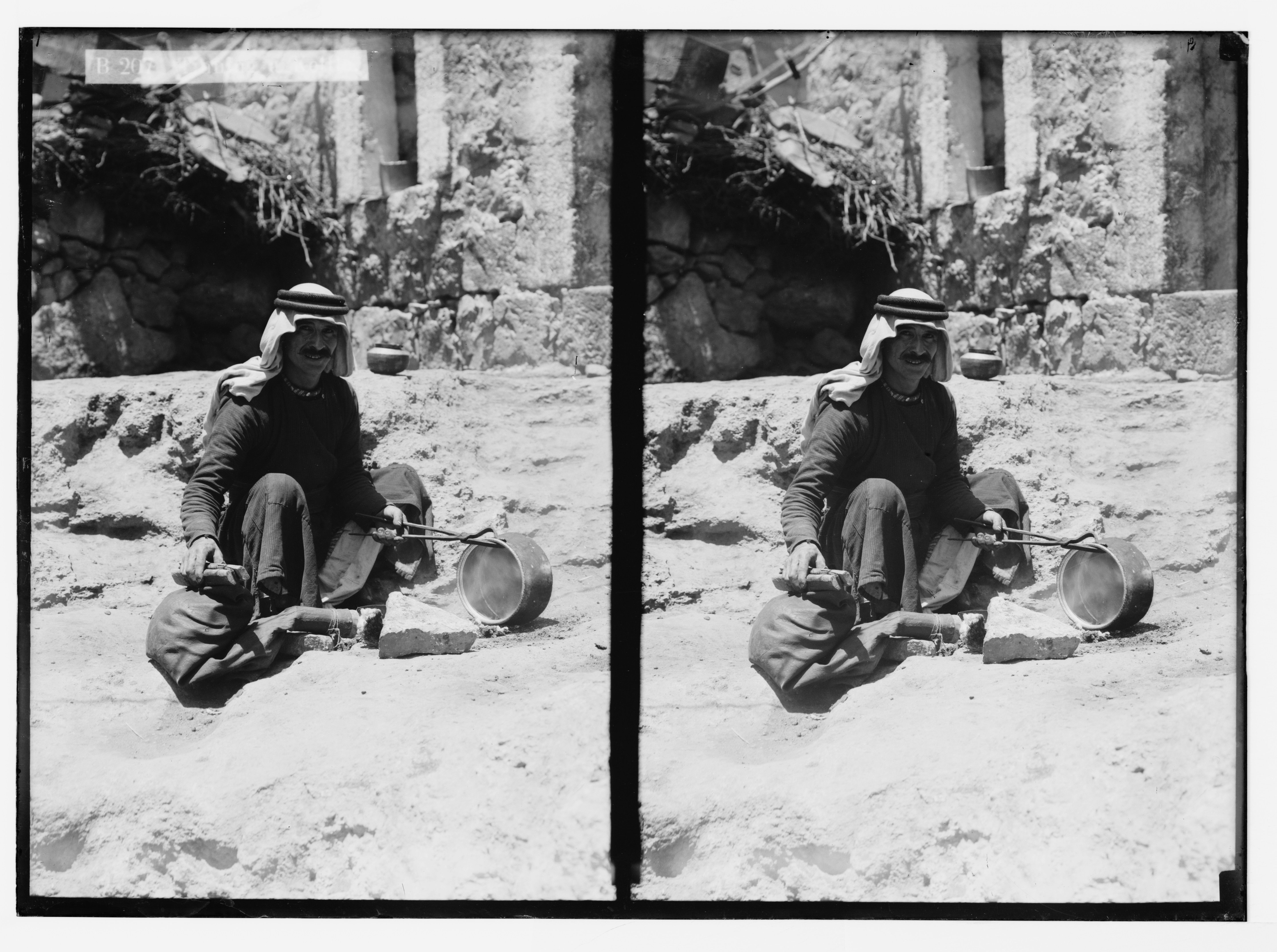 Stereoscopic photograph of a man sitting on the ground with a pot in his hands, wearing traditional Middle Eastern clothing.