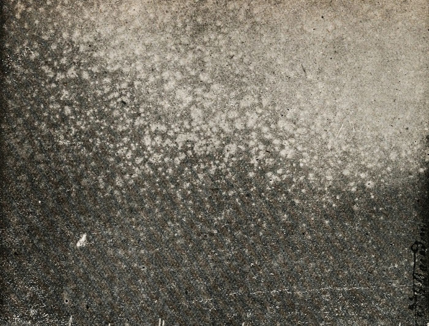 A close-up of a heavily textured surface with a vintage or aged appearance, covered in small spots and speckles.