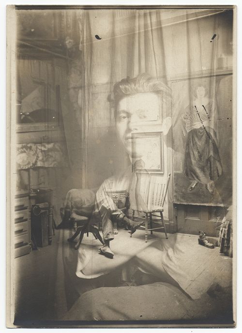 A vintage sepia-toned photograph with a ghostly woman superimposed onto a cluttered room interior. A miniature table and chairs are set up in the foreground, creating a sense of scale distortion.