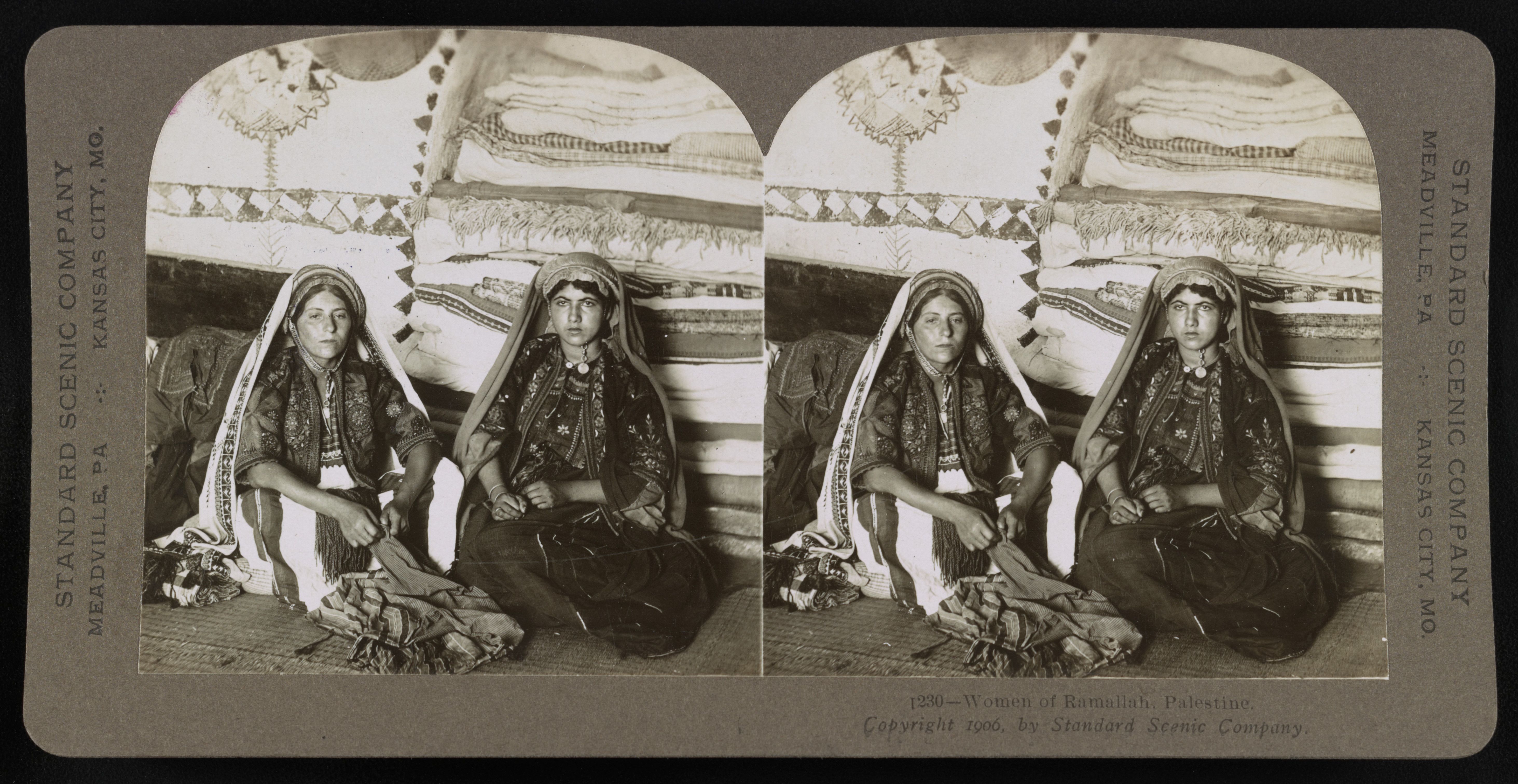 Stereoscopic photograph of two women in traditional Palestinian clothing sitting in front of a stone wall.