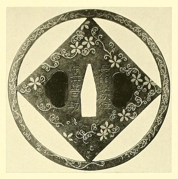 Antique Japanese tsuba with floral pattern and diamond shapes.