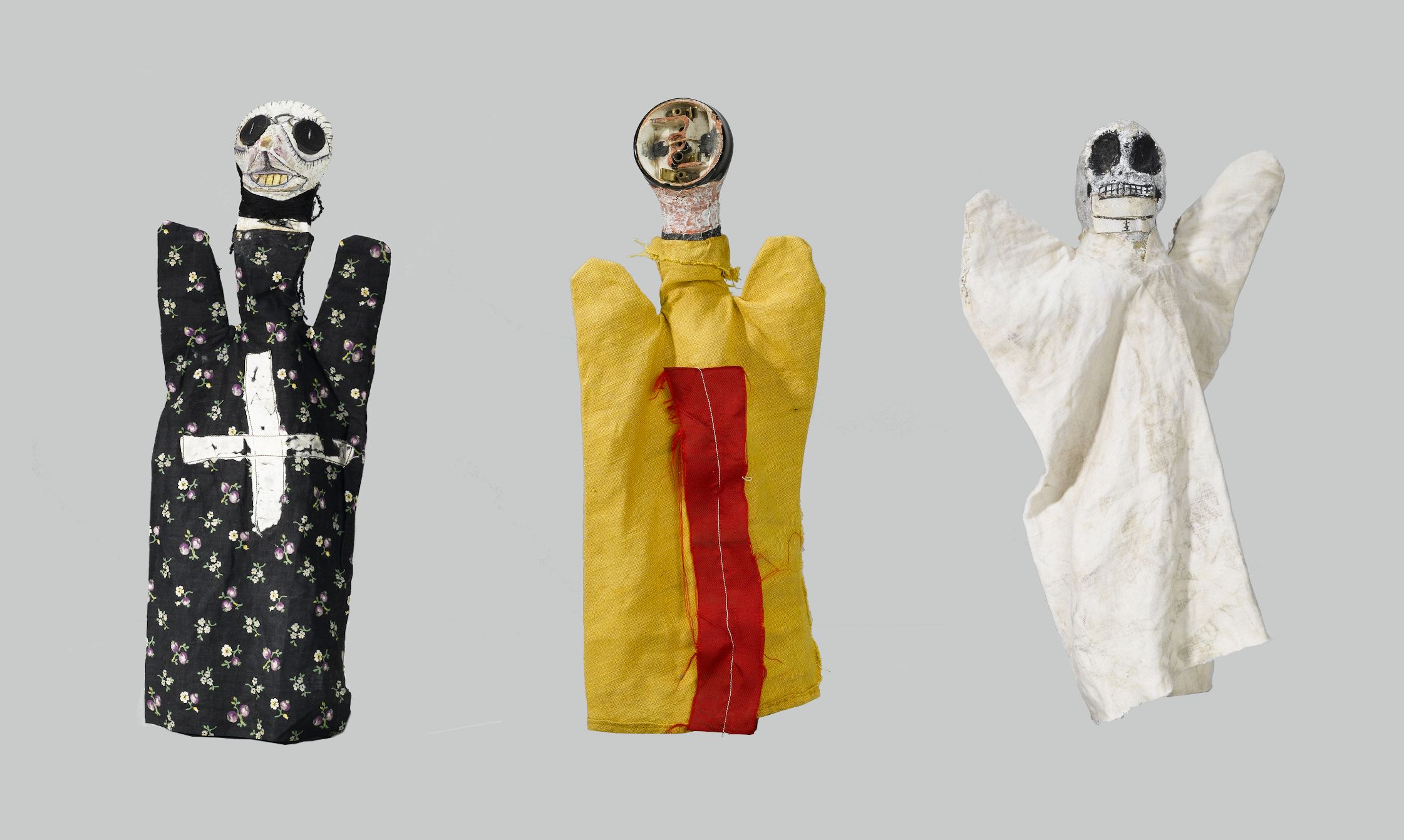 Three hand puppets dressed in unique costumes and masks against a light gray background.