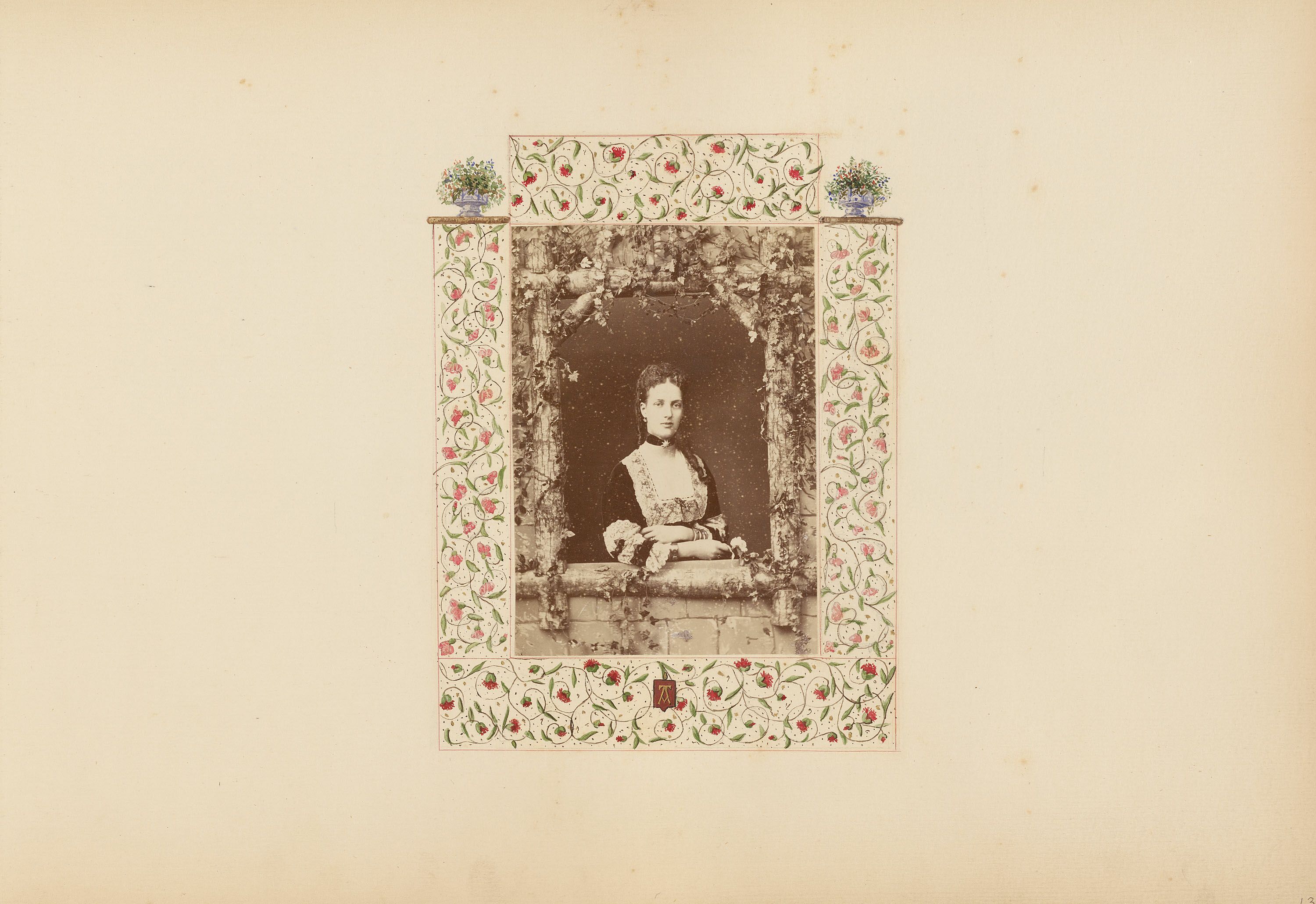 A sepia-toned vintage photograph of a woman seated at a table, framed by an ornate floral border.