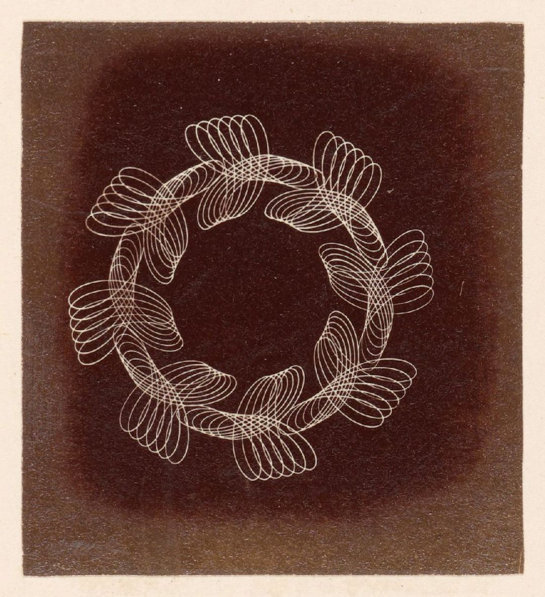 Sepia-toned photograph of a circular pattern created by delicate, looping lines.