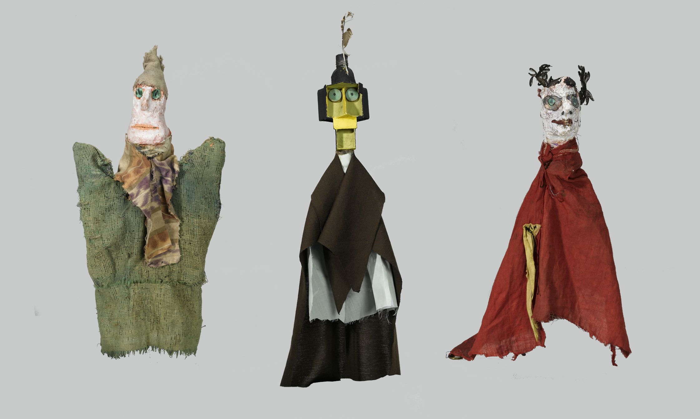 Three handmade puppets or dolls against a light gray background.