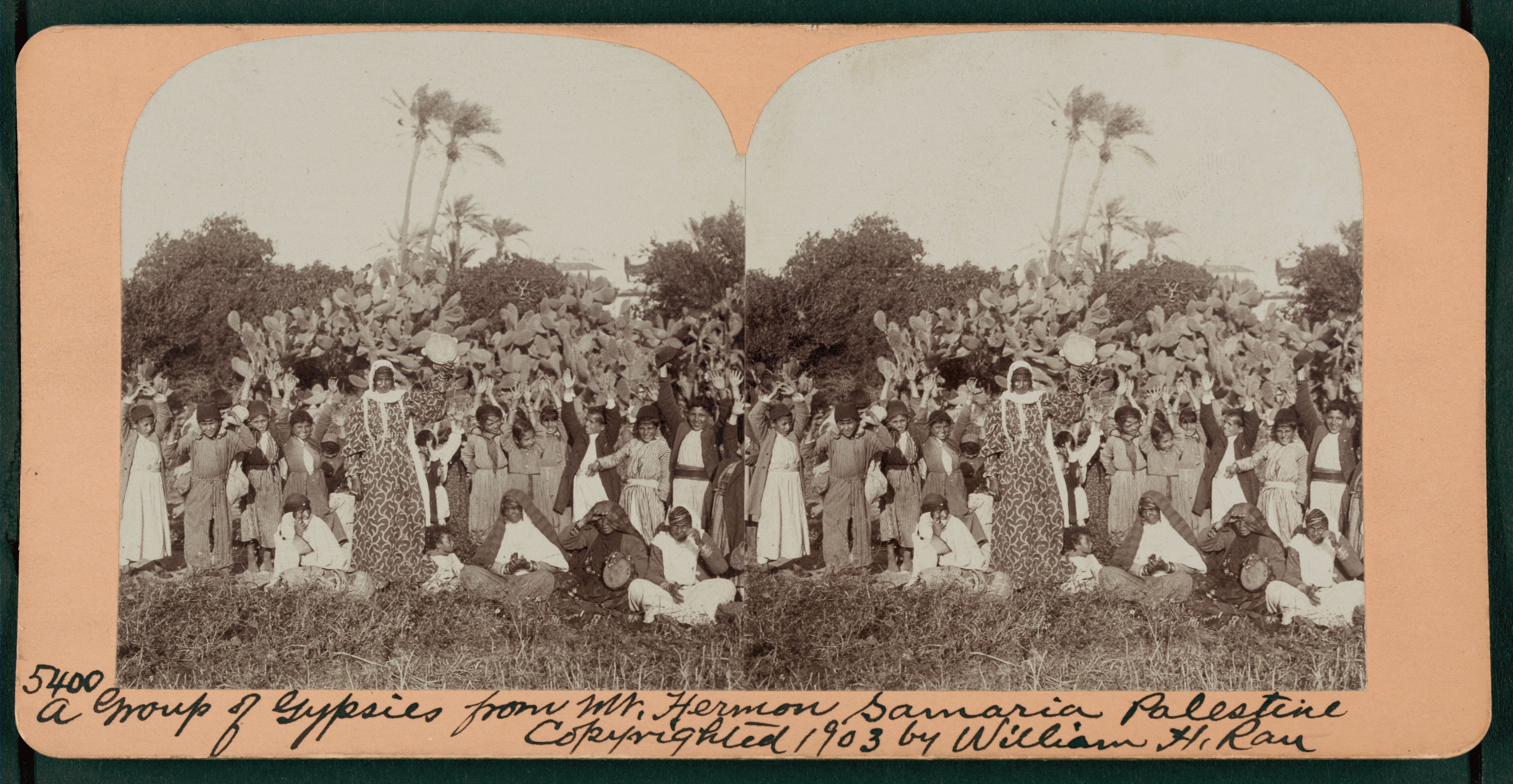 Stereoscope card of a large group of people identified as "Gypsies from Mt. Hermon Samaria Palestine" standing in a hilly landscape.