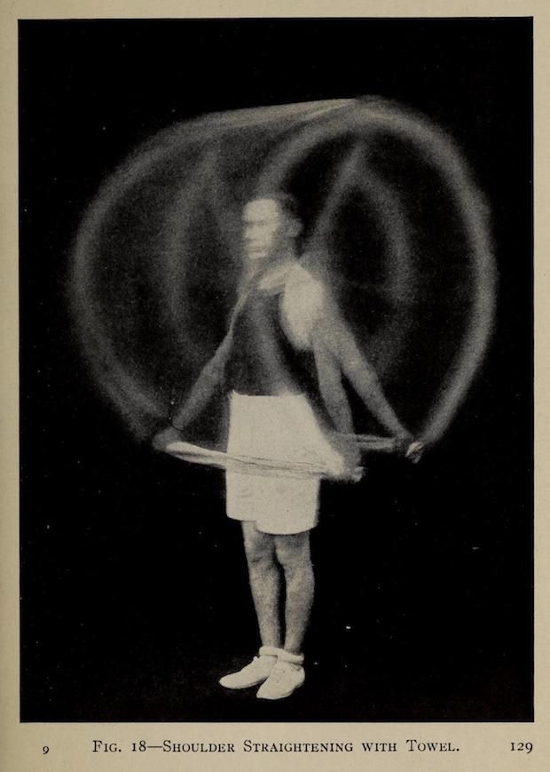 Vintage black and white photograph of a person performing a shoulder straightening exercise with a towel.