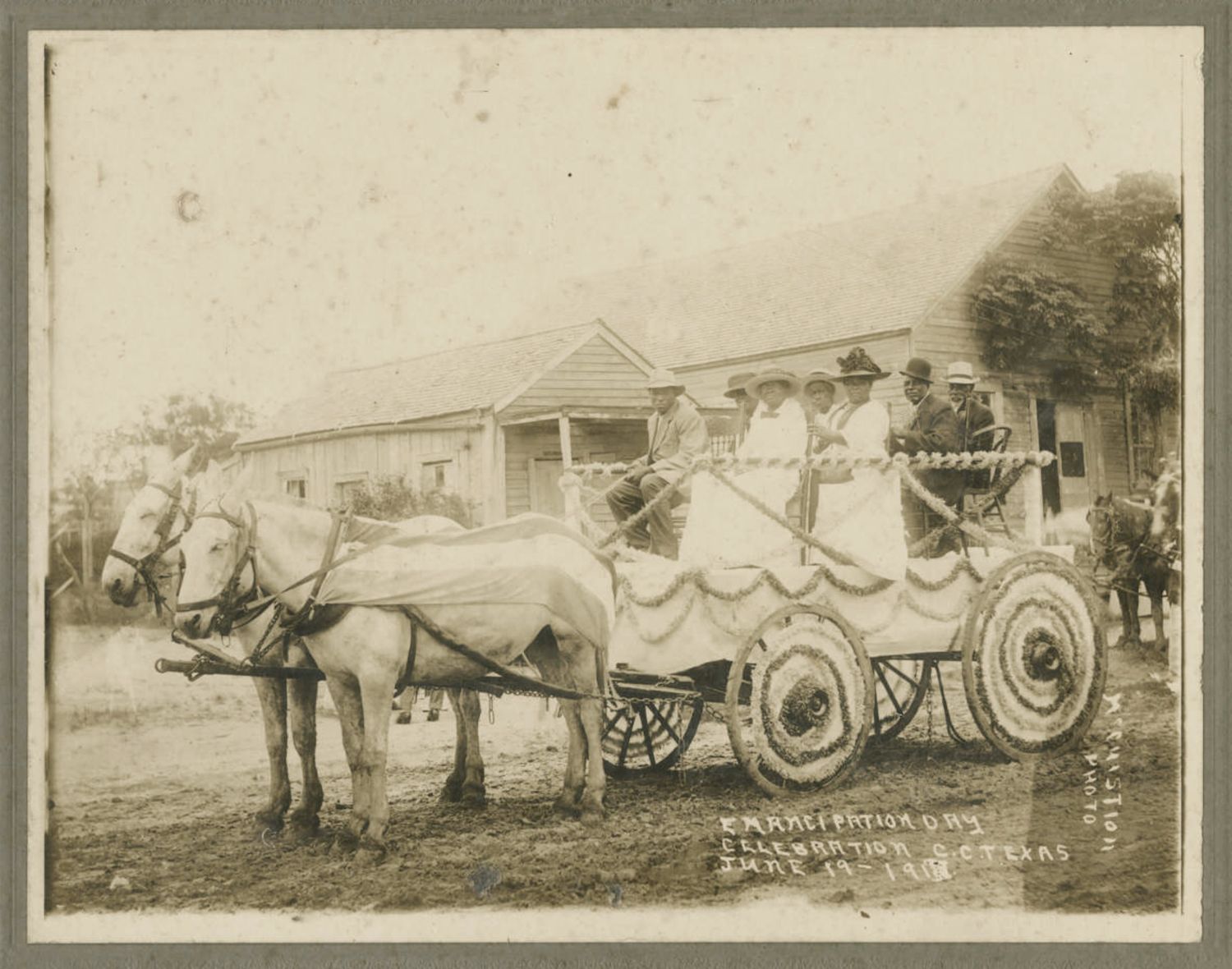 A vintage black and white photograph of an Emancipation Day celebration in Texas, dated June 19, 1918, featuring a horse-drawn carriage with people inside and a building in the background.