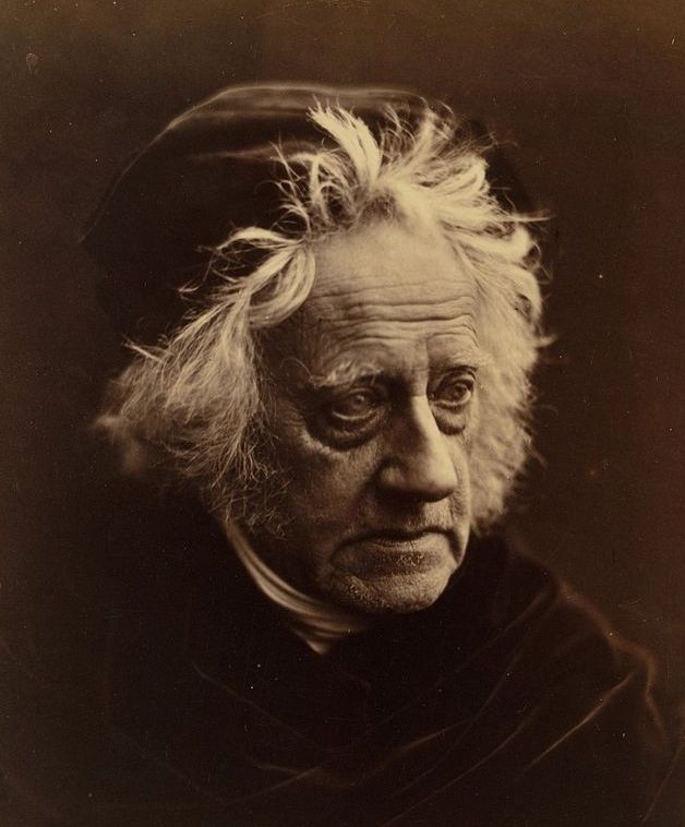 Sepia-toned portrait of an elderly man with wild, white hair and a serious expression.