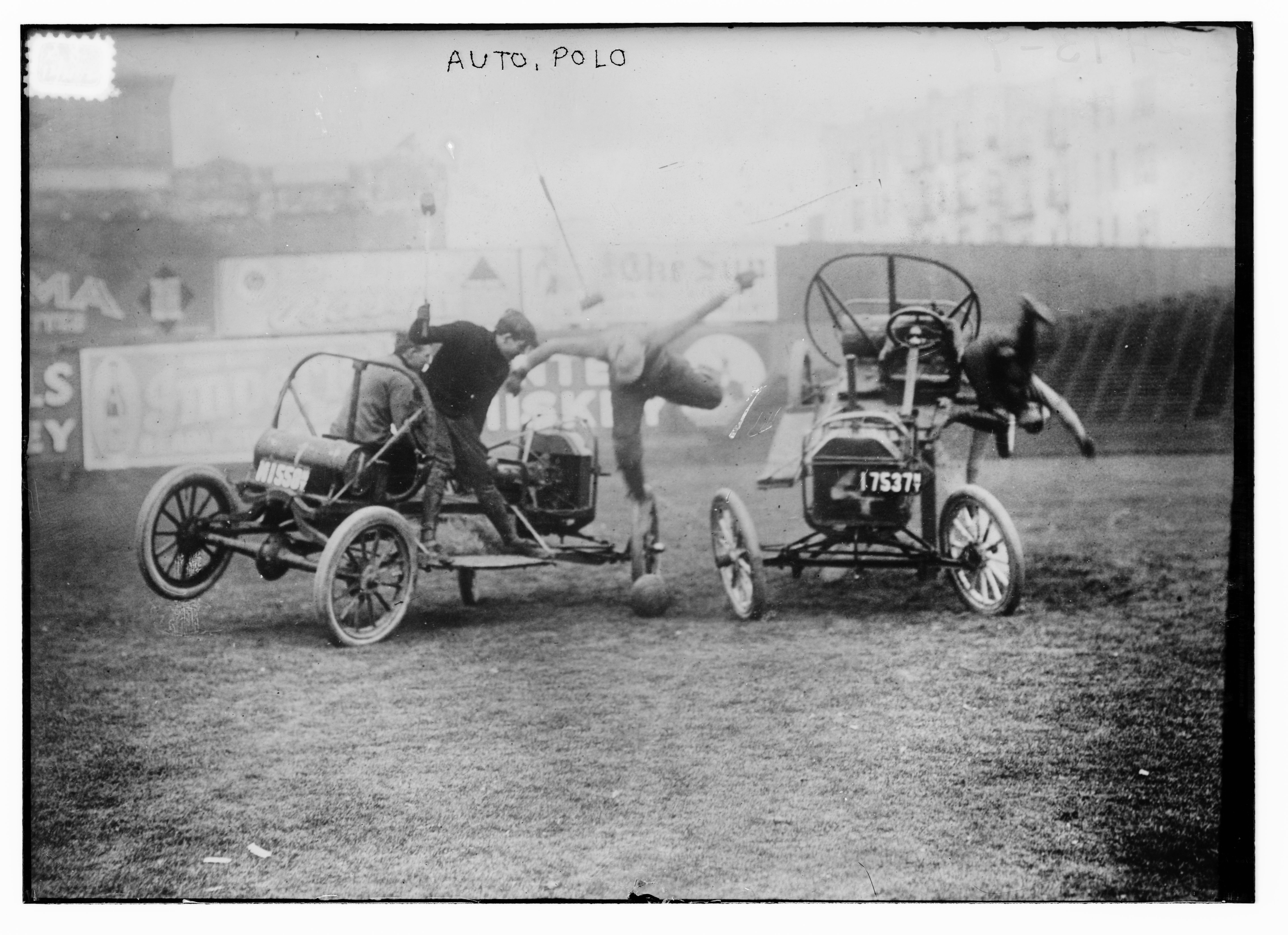 Black and white photograph of two vintage automobiles engaged in an auto polo match on a grassy field.
