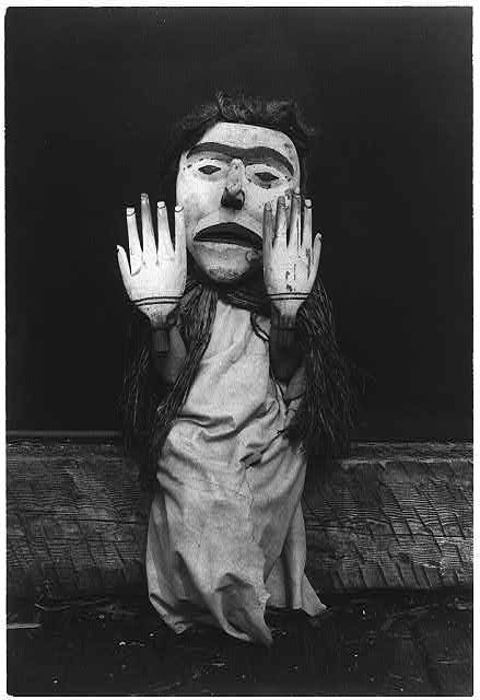 A black and white photograph of a Kwakwaka'wakw mask and figure.
