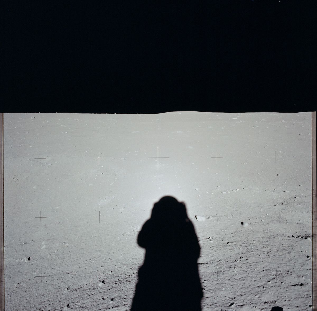 A black and white photograph of an astronaut silhouetted against the lunar landscape.