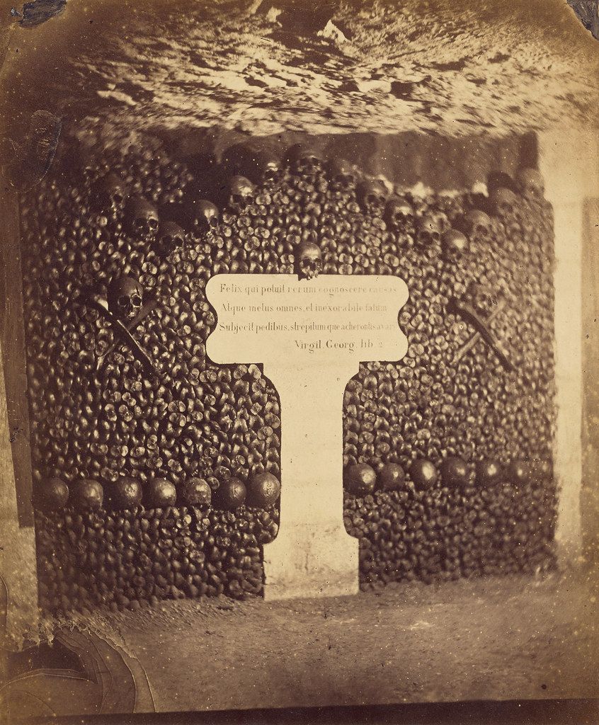 A sepia-toned photograph of a weathered tombstone in a graveyard.