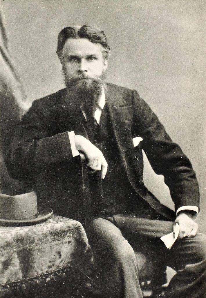 A vintage black and white portrait of a man in a suit with a full beard and mustache.