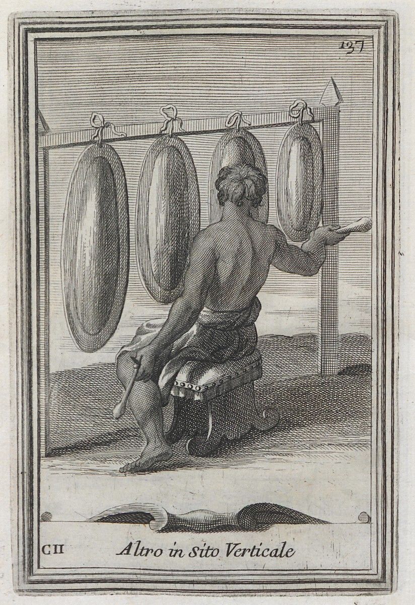 A black and white engraving of a muscular man seated on a stone block, working with large oval-shaped objects suspended from a wooden structure.
