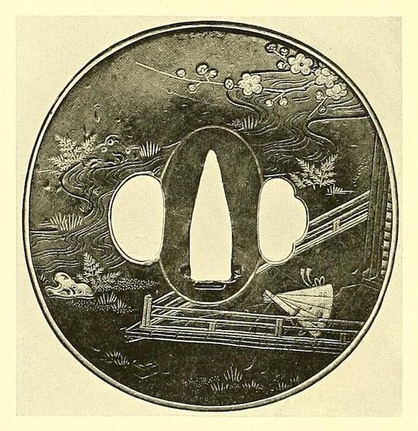 A detailed, circular tsuba with a miniature landscape carved into it, featuring a bridge, cherry blossoms, and a butterfly.