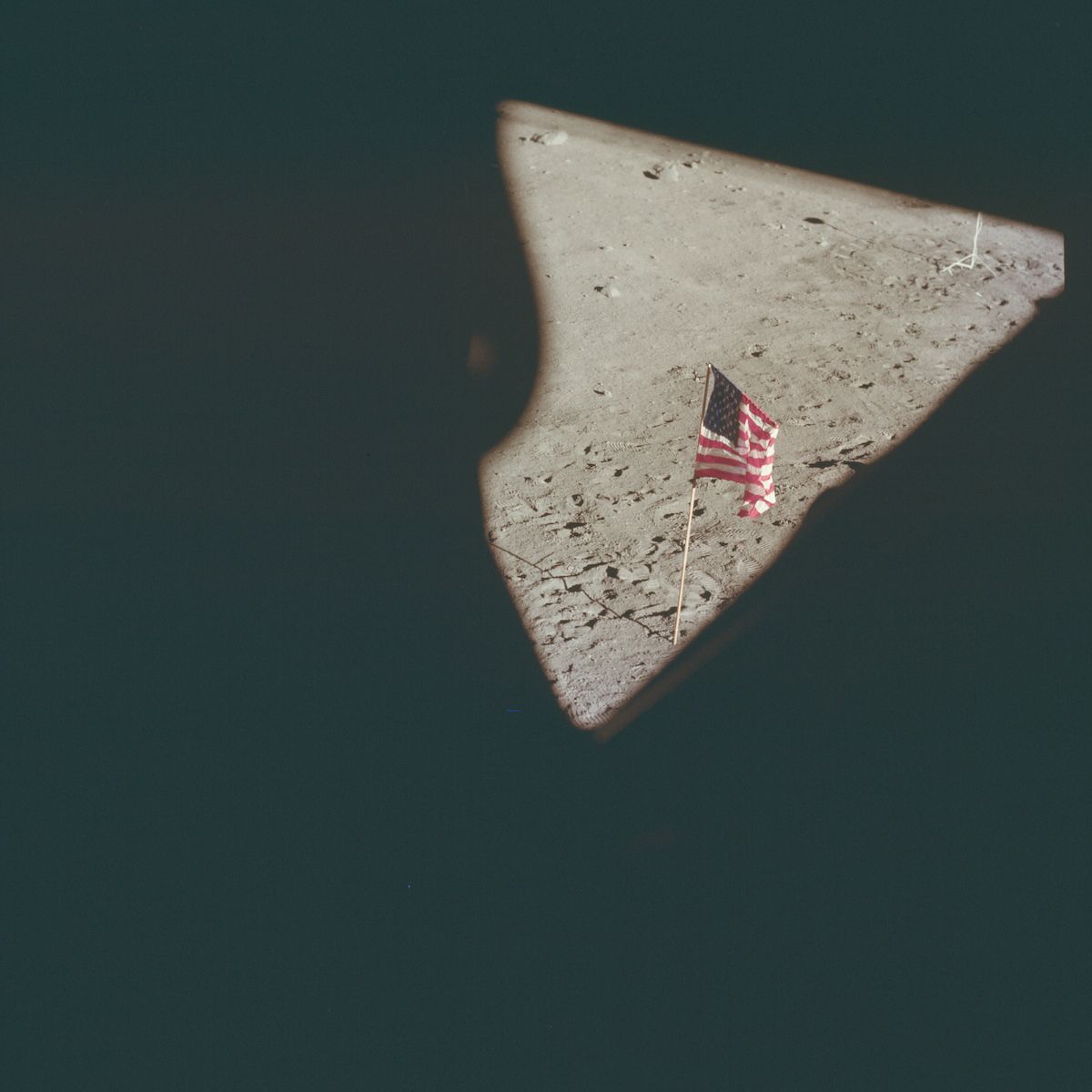 American flag on the moon, framed by a dark shadow.