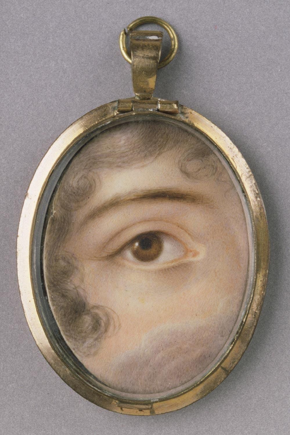 Close-up of an eye in an oval locket.
