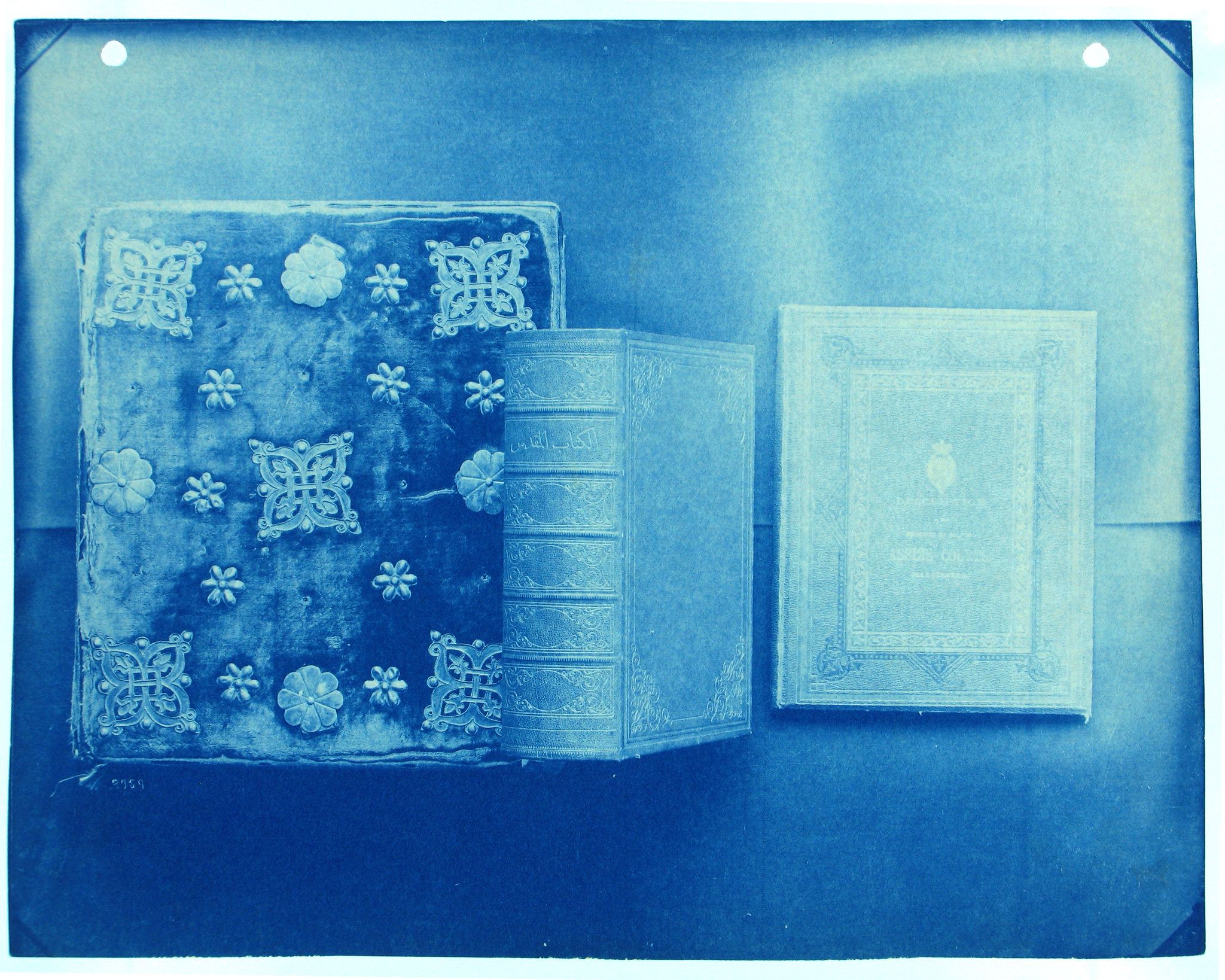 Cyanotype photograph of an antique album, a spine-bound book, and a smaller book.