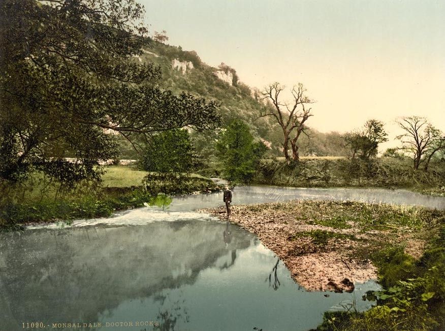 Vintage colorized photograph of Monsal Dale, Doctor Rocks, featuring a river flowing through a valley with a cliff in the background.