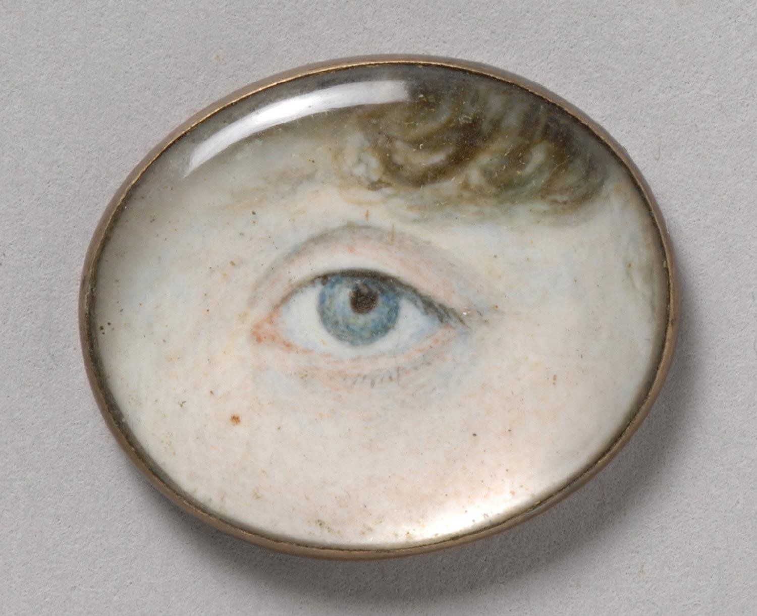 Close-up of a blue eye painted on an oval surface and framed in gold.