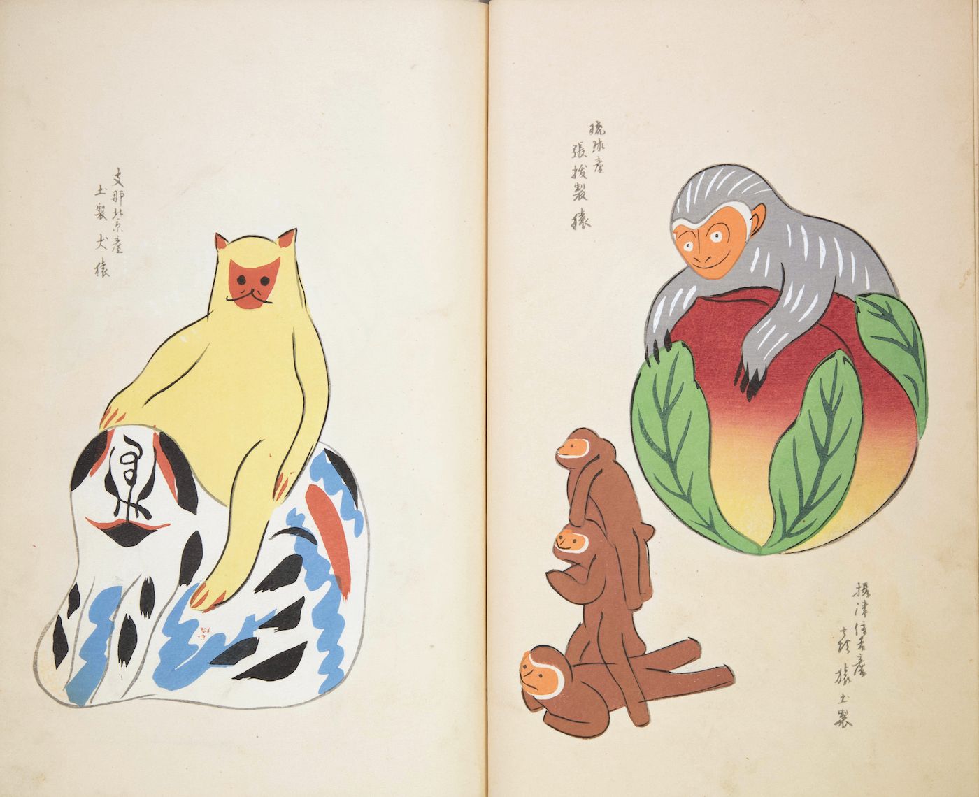 A double-page spread from a Japanese woodblock print book featuring two illustrations of monkeys. The left page shows a tan monkey sitting on a cylindrical object with a black and white pattern. The right page depicts a larger reddish-brown monkey with a grey mane, surrounded by green leaves, and two smaller tan monkeys clinging to its body.