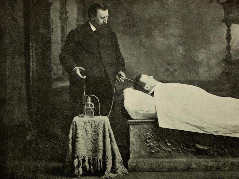A vintage black and white photograph of a doctor attending to a patient in bed.