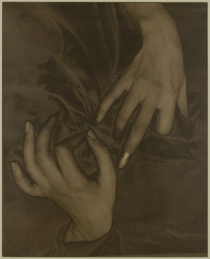 Close-up sepia-toned photograph of two hands gently touching.