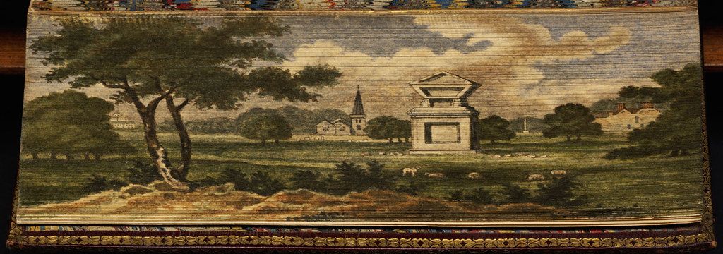 A woven rug depicting a pastoral landscape with trees, buildings, and animals.