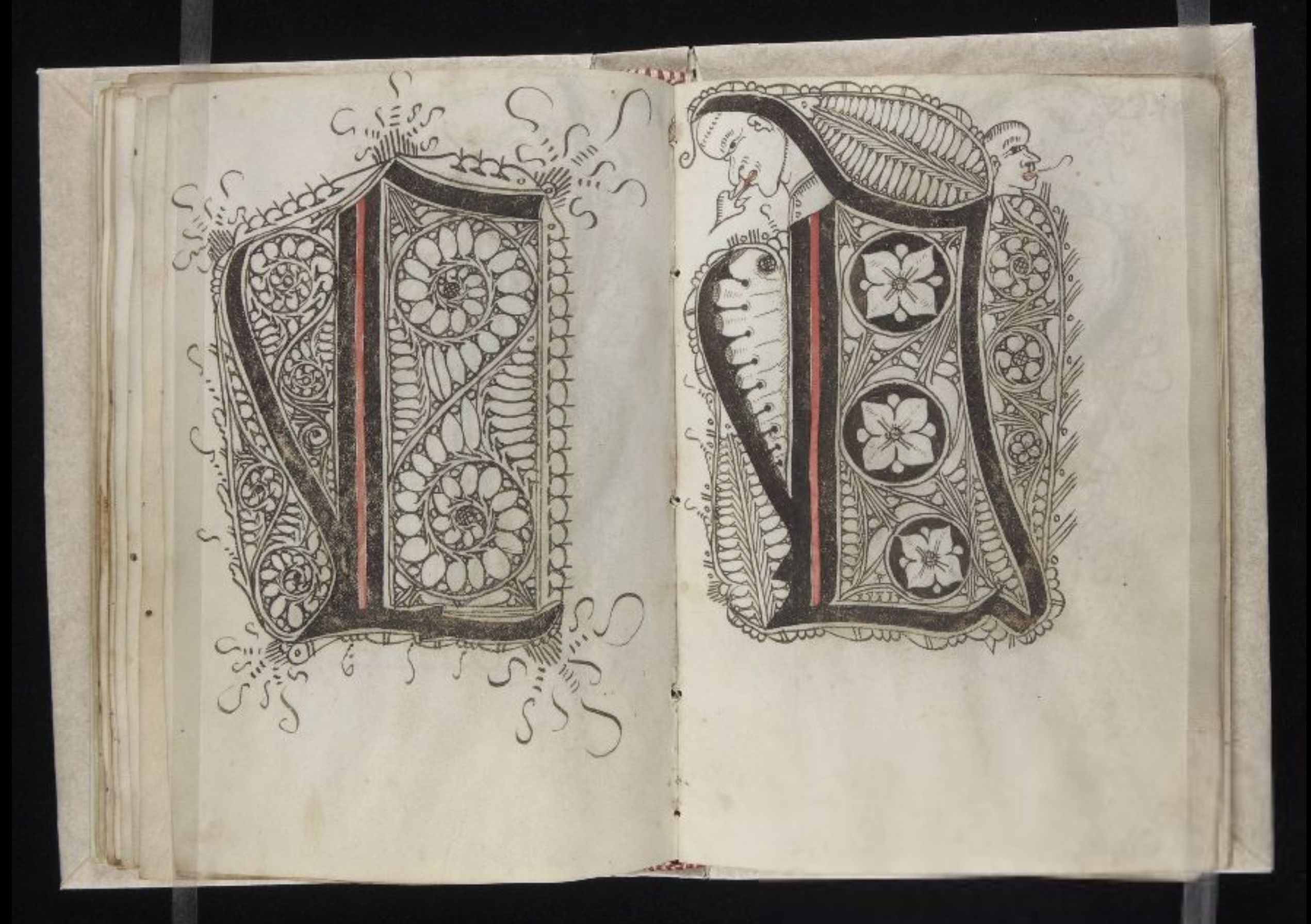 Open book with two pages featuring ornate letter 'V' designs.