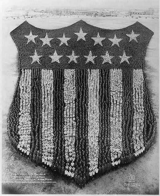 A black and white photograph of a living American flag formed by soldiers.