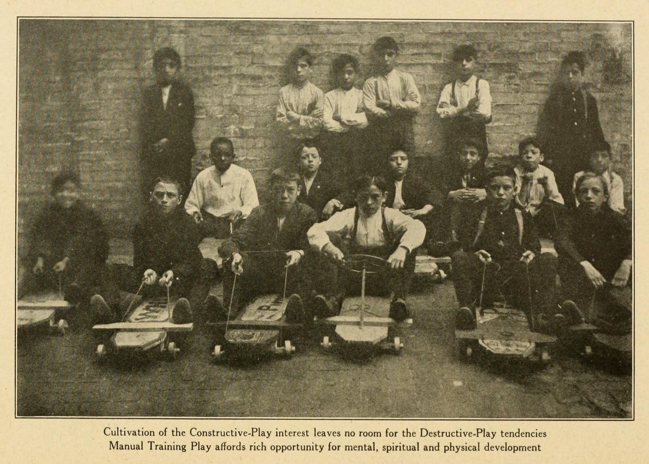 A vintage black and white photograph of a group of boys engaged in manual training in a classroom or workshop setting.