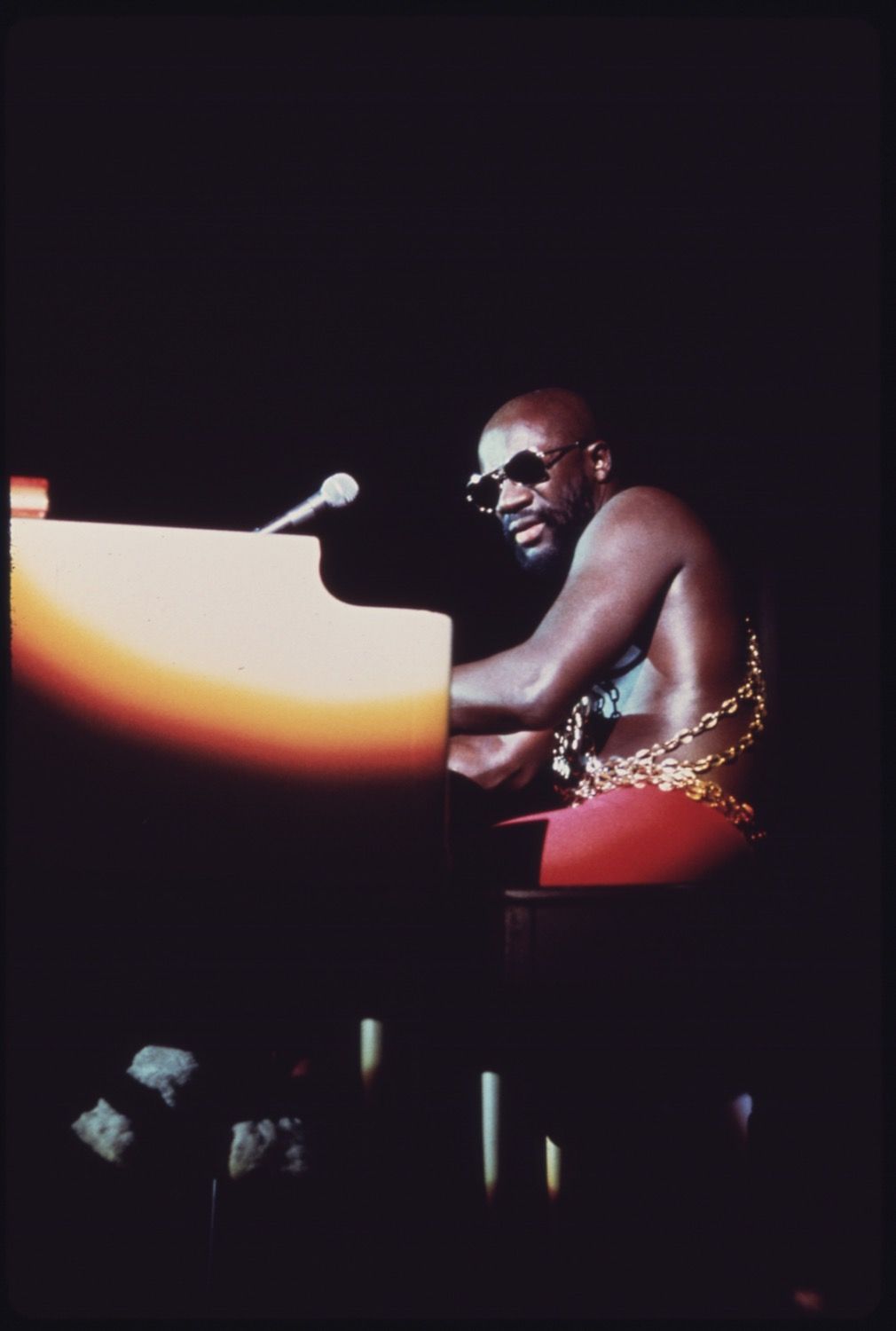 A man playing a piano on a dark stage.