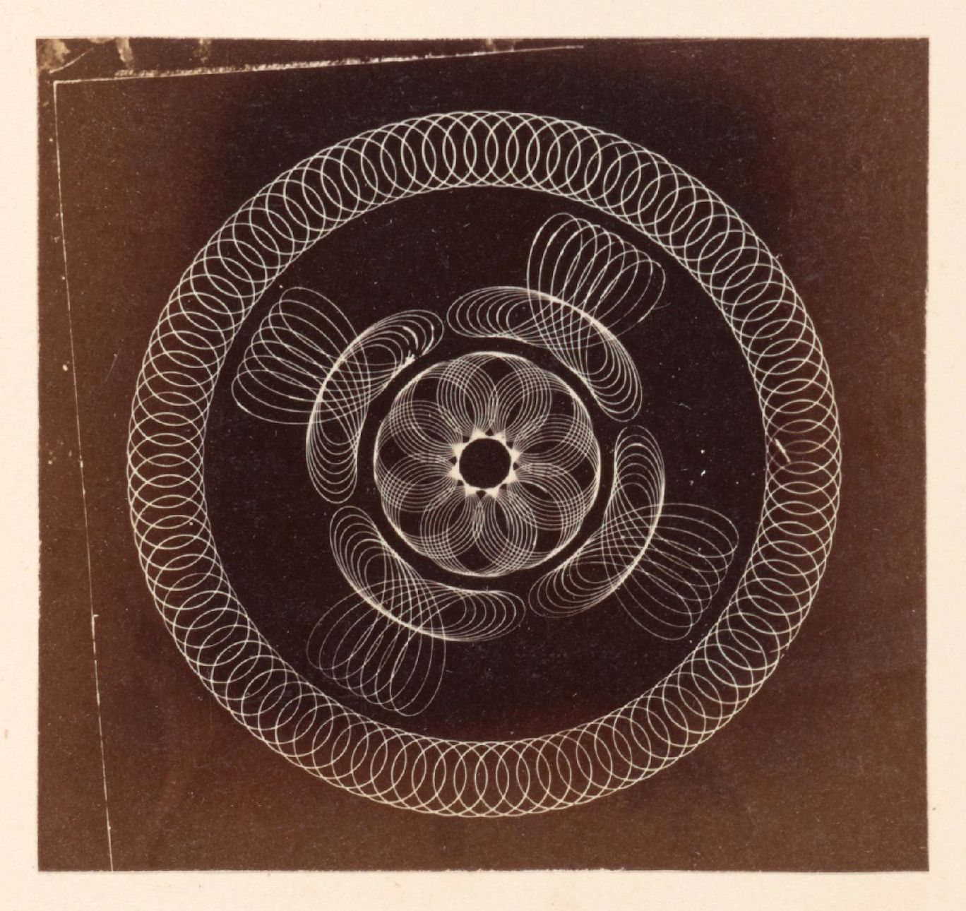 A vintage photograph of a complex geometric pattern with concentric circles and swirling lines against a dark background.